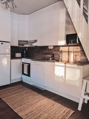 Eine moderne Küche mit weißen Schränken, einer Holzspritzschutzleiste und einem eingebauten Backofen.