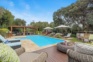 Ein Poolbereich mit Liegestühlen, einer Pergola und einem Pavillon.