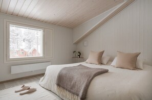 Un dormitorio con una cama grande, una ventana y un techo inclinado.