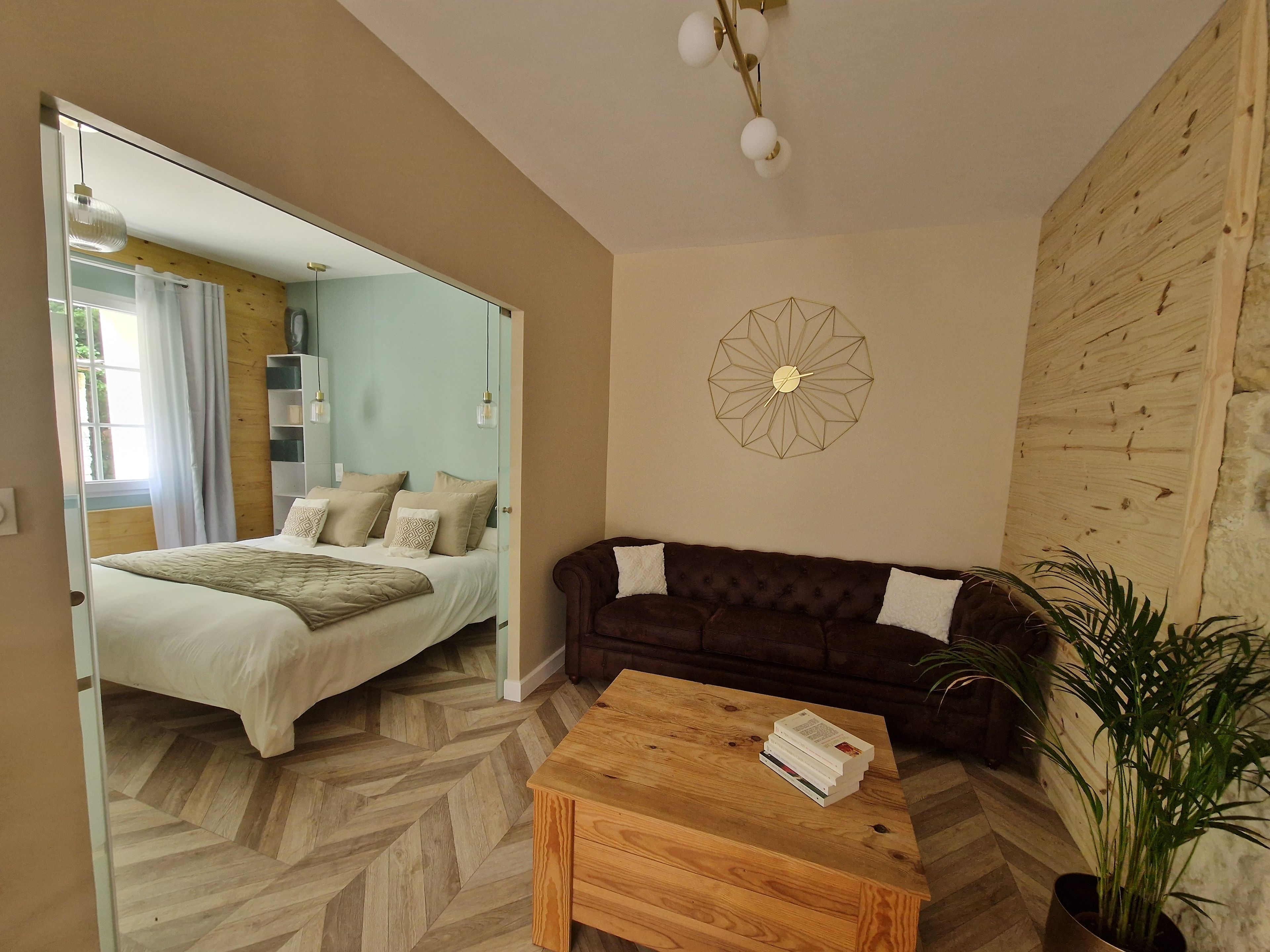 A room with a bed, a sofa, a coffee table, and a wall clock.