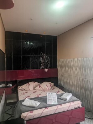 A hotel room with a bed, a mirror, and a wall with a wavy pattern. - Santo Amaro inn (São Paulo)