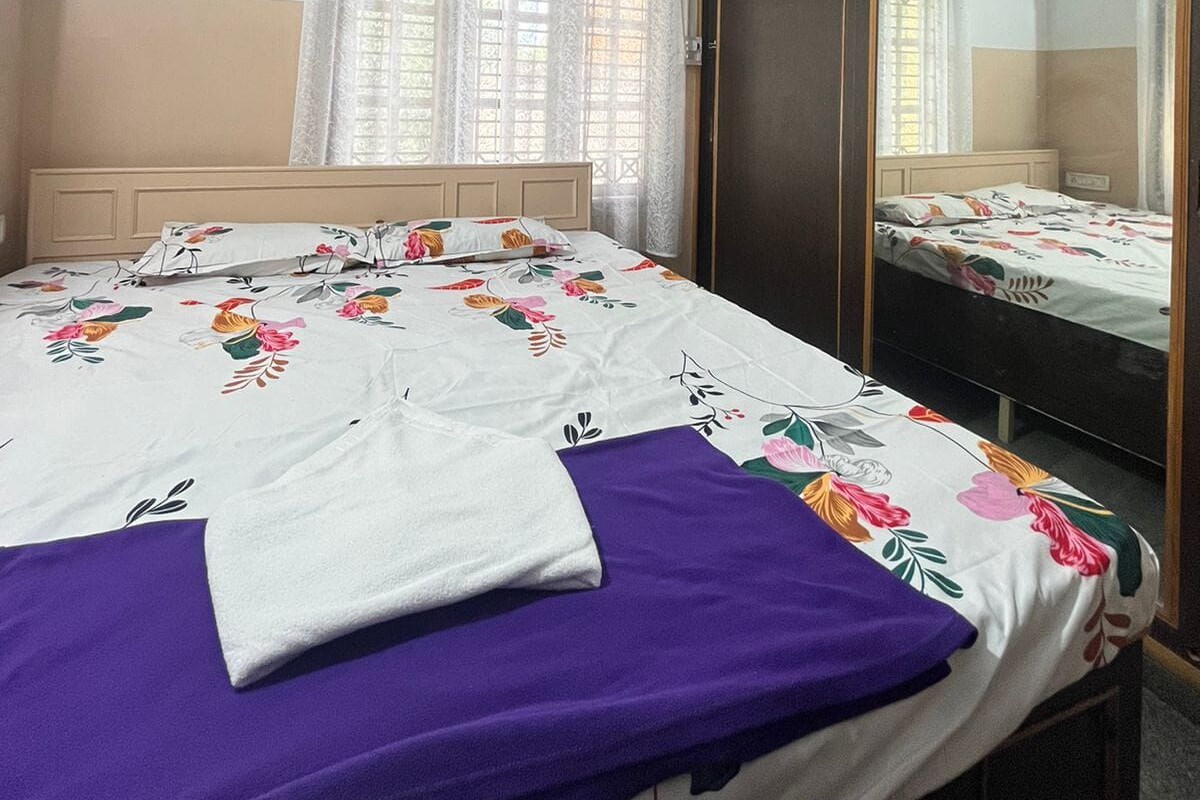 Une chambre à coucher comprenant un lit, une armoire, un miroir, un appareil de climatisation et une fenêtre avec des rideaux.