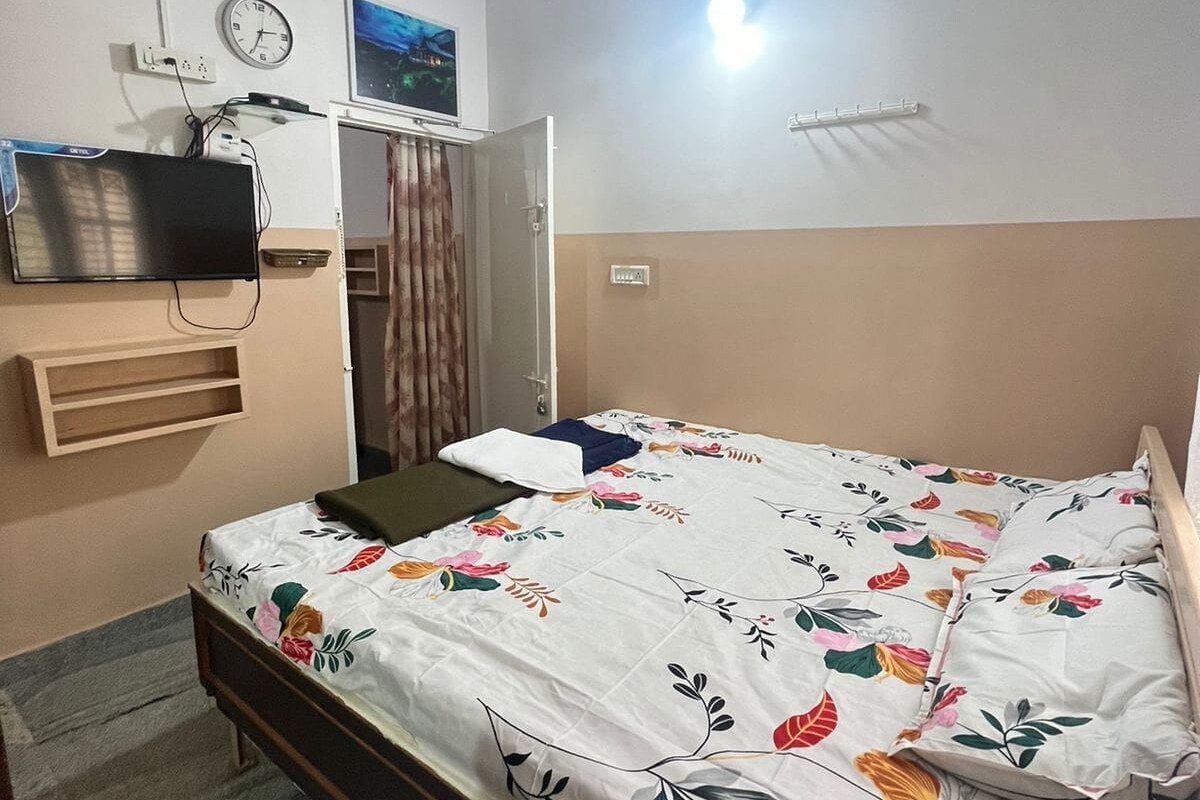 Une chambre à coucher avec un lit, un ventilateur de plafond, un téléviseur fixé au mur et une table de chevet.
