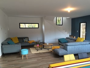 Una sala moderna con un sofá gris, una mesa de centro y un sillón azul.