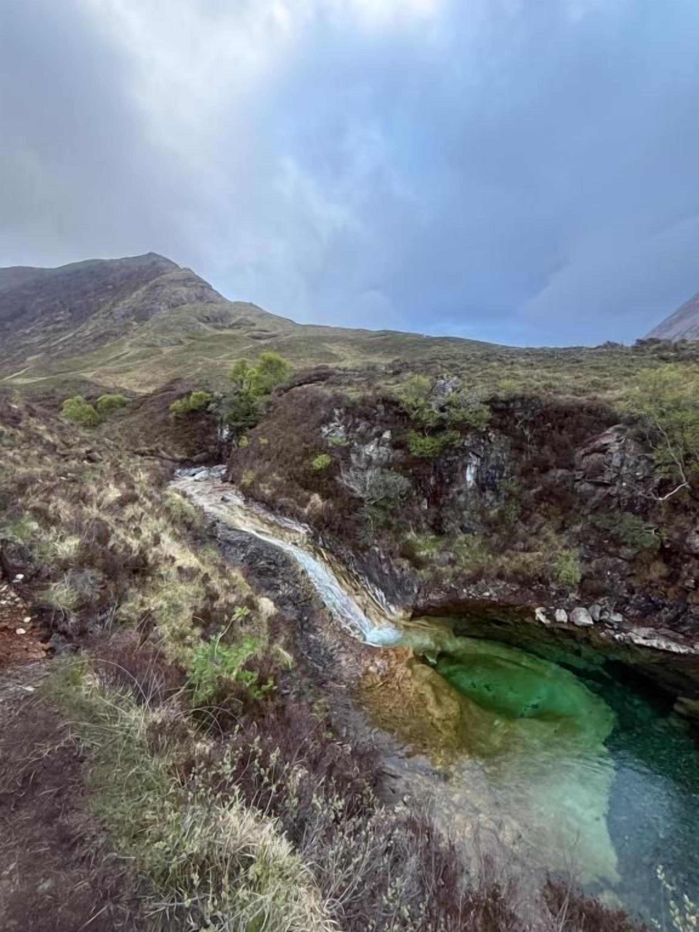 Un paysage naturel caractérisé par un cours d’eau, un terrain rocheux et une végétation clairsemée.
