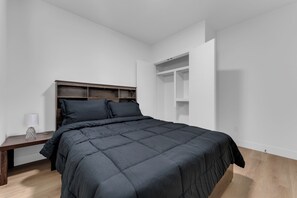 Une chambre à coucher comprenant un lit, une table de chevet, une lampe et une bibliothèque intégrée.