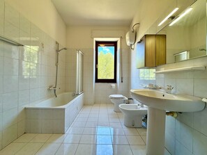 Une salle de bain moderne équipée d’une baignoire, de toilettes, d’un bidet et d’un grand lavabo.
