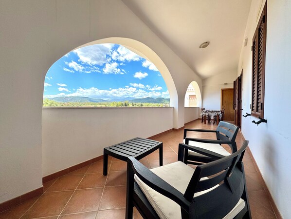 Un balcon avec vue sur les montagnes, une table et des chaises.