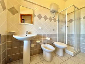 Une salle de bain équipée d’un lavabo, d’un bidet, de toilettes et d’une douche à parois de verre.