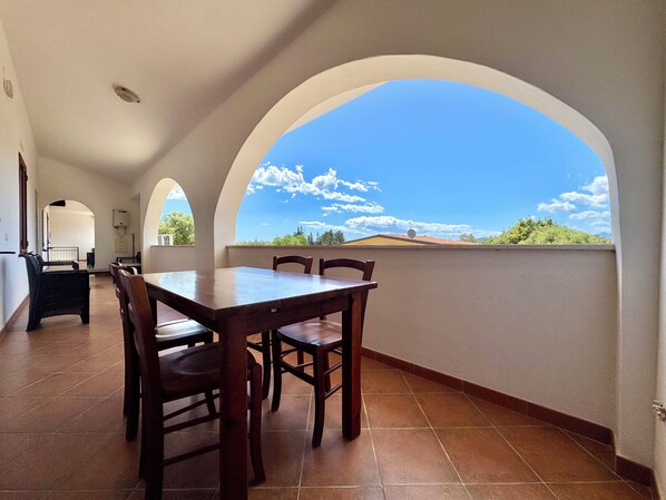 Un espace repas comprenant une table et des chaises, de grandes fenêtres en arc de cercle et une vue sur le paysage.
