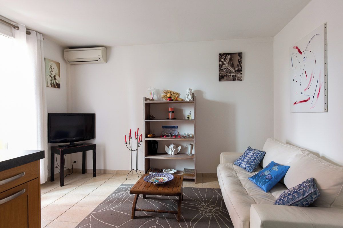 Un salon comprenant un canapé, une table basse, un téléviseur, une bibliothèque et un climatiseur fixé au mur.