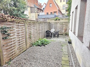 Ein Innenhof mit Holzzaun, Kiesfläche und einem Tisch mit Stühlen.