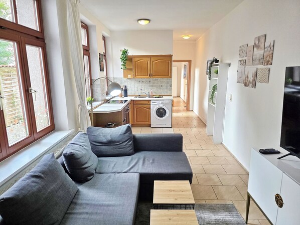 Ein modernes Wohnzimmer mit einem grauen Sofa, einem kleinen Holztisch und einer TV-Konsole.