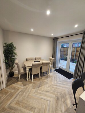 A dining area with a table and chairs, a potted plant, and a view through a glass door. - 3 bedroom home in Horsham (Southwater)