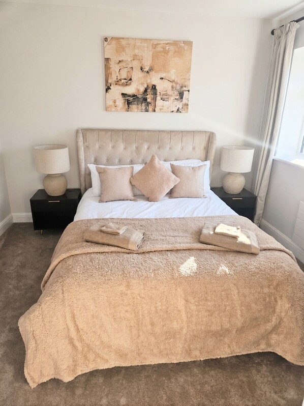 A bedroom with a large bed, two bedside tables, a headboard, and a painting on the wall. - 3 bedroom home in Horsham (Southwater)