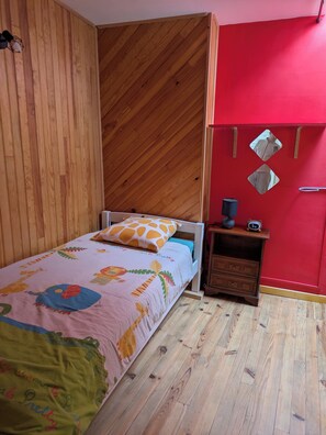 Ein Schlafzimmer mit einem Bett, einem Nachttisch, einer roten Wand und Holzvertäfelung.