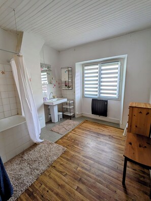 Ein Badezimmer mit Dusche, Waschbecken und Fenster.