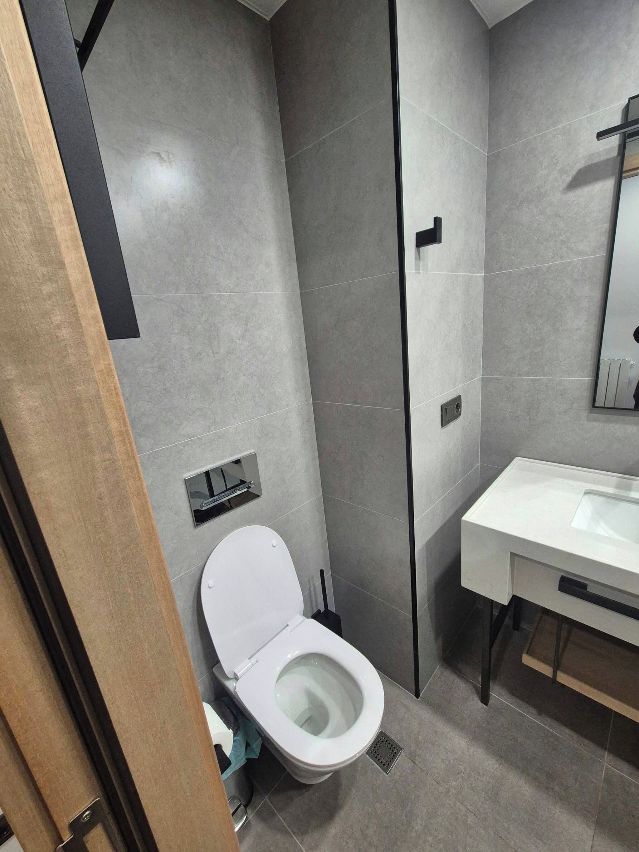 Un baño moderno con inodoro, lavamanos y espejo.
