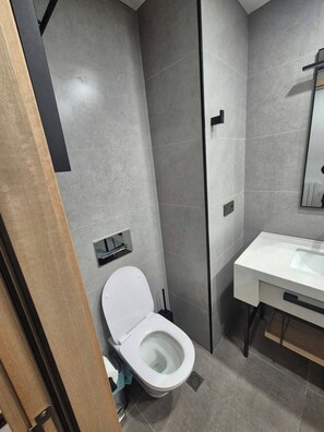 A modern bathroom with a toilet, sink, and mirror. - Cozy Apartment for rent in Batumi! Stadium View (Batumi)