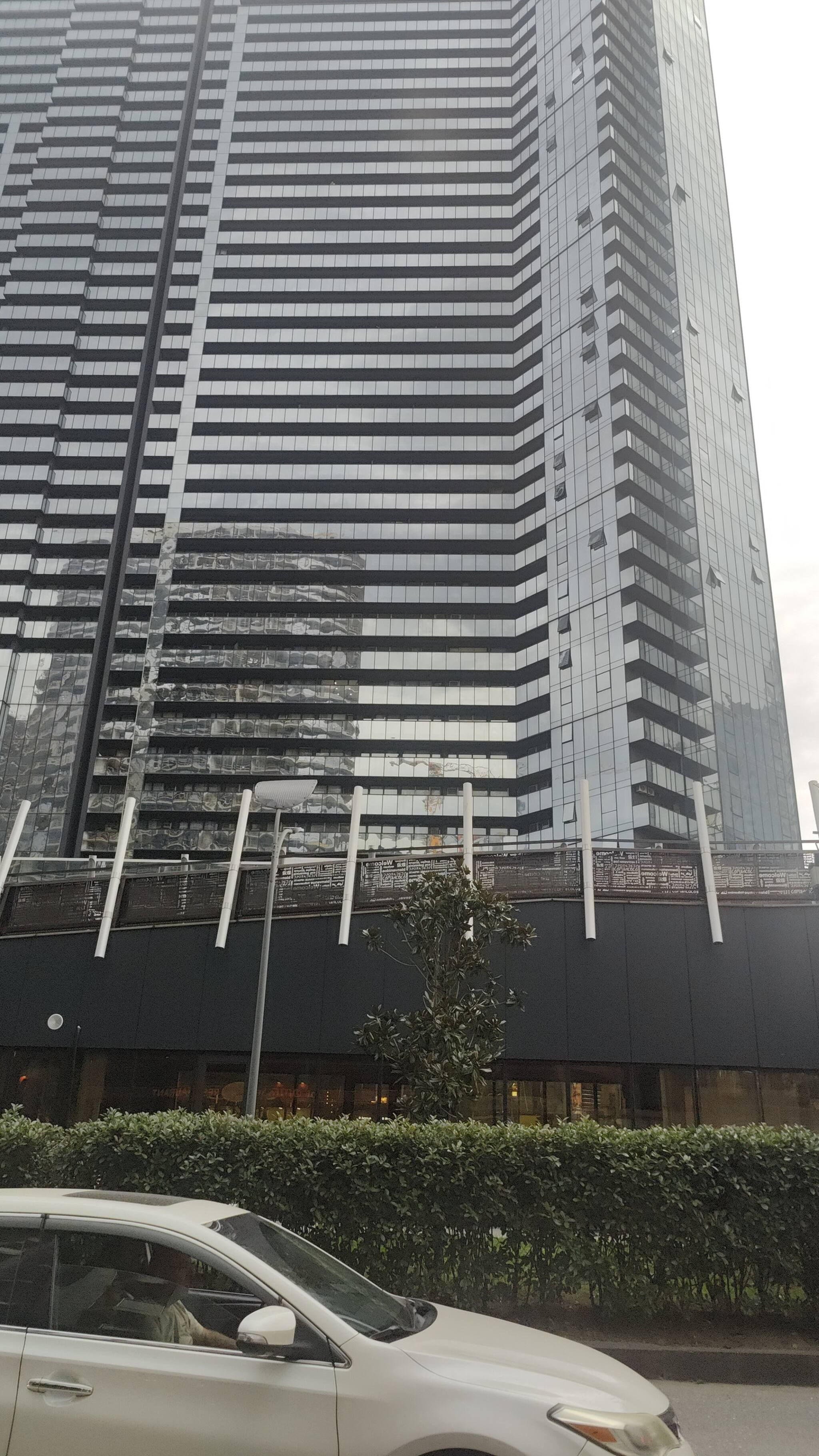 Un edificio alto y moderno con fachada de vidrio reflectante y varias terrazas.