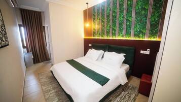 A hotel room with a bed, a green accent pillow, a wall with vertical stripes, and a window.