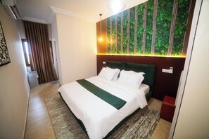 A hotel room with a bed, a green accent pillow, a wall with vertical stripes, and a window. - New Listing (Lomé)
