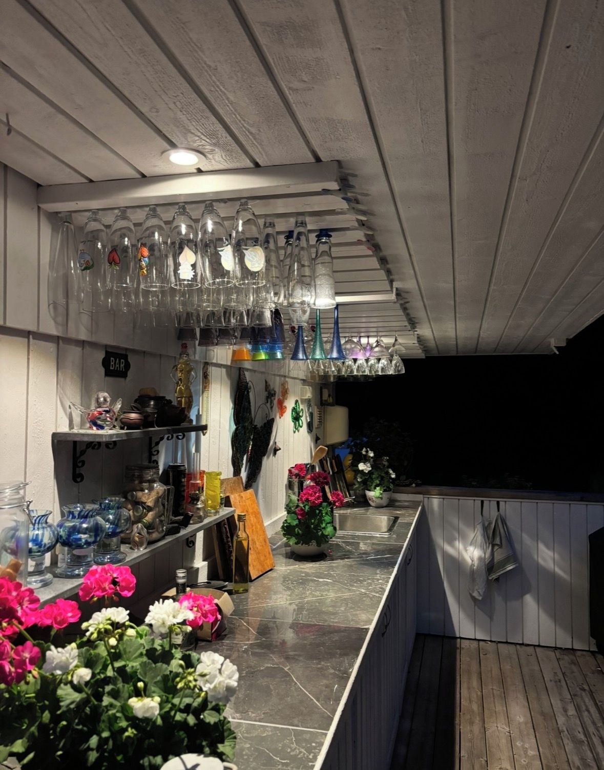 Uma área de bar com prateleiras de copos e diversos tipos de garrafas.