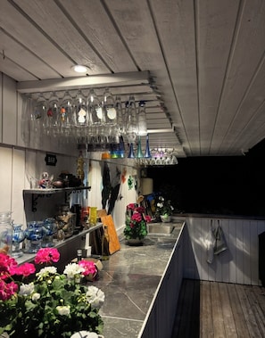 Uma área de bar com prateleiras de copos e diversos tipos de garrafas.