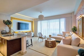A modern living room with a sofa, a coffee table, and a TV mounted on the wall. - Beachfront apartment on the 9th floor of Las Olas, Juan Dolio — panoramic ocean views, infinity pool, and 24/7 reception. (Juan Dolio)