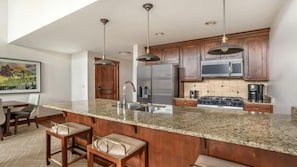 Cocina moderna con encimeras de granito, electrodomésticos de acero inoxidable y armarios de madera.