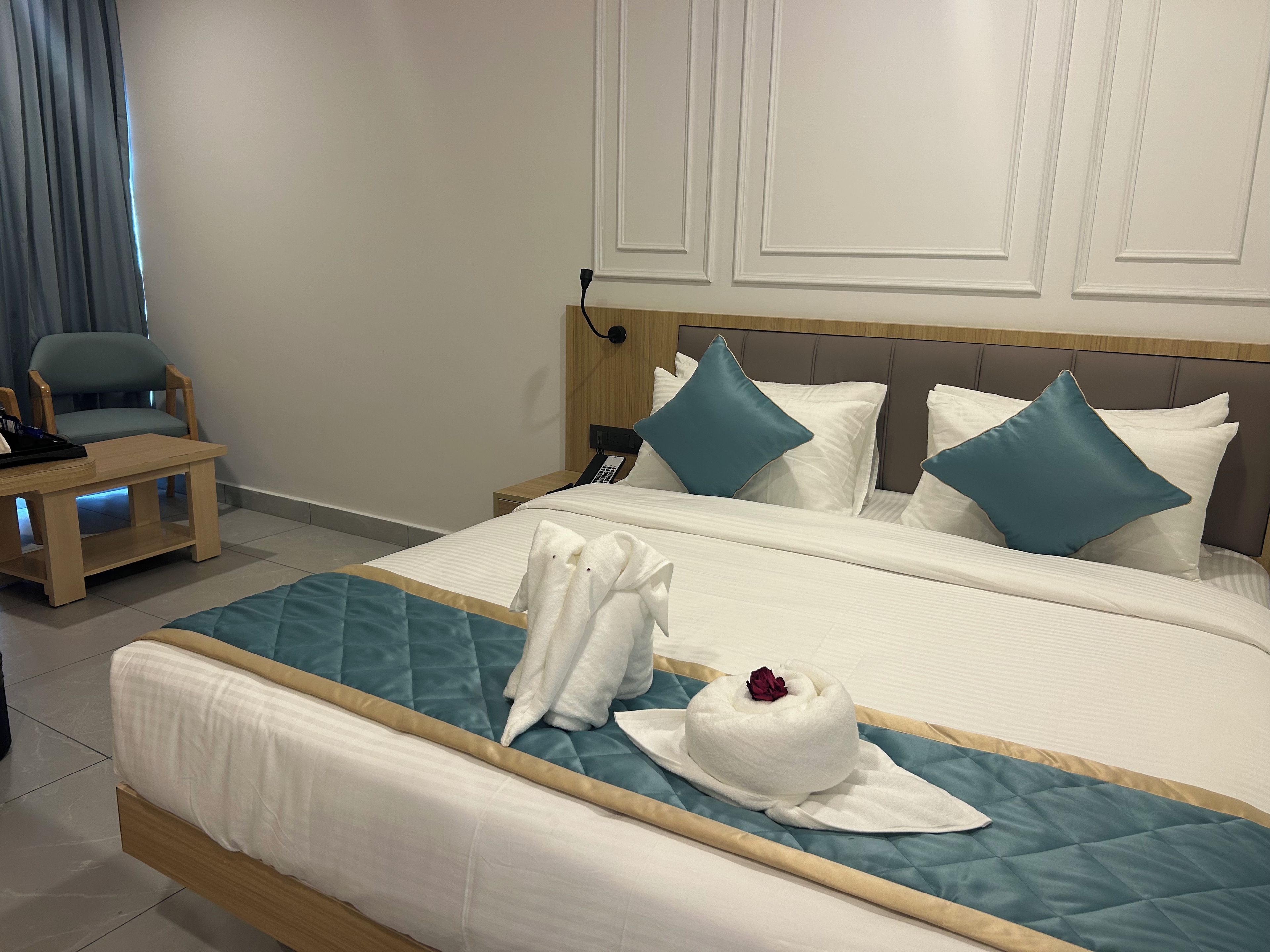 Ein Hotelzimmer mit einem Bett, einem Nachttisch, einem Sessel und einem an der Wand befestigten Telefon.