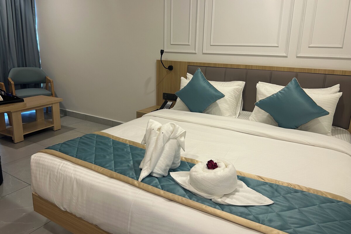 Quarto de hotel com cama, mesa de cabeceira, cadeira e telefone fixado na parede.