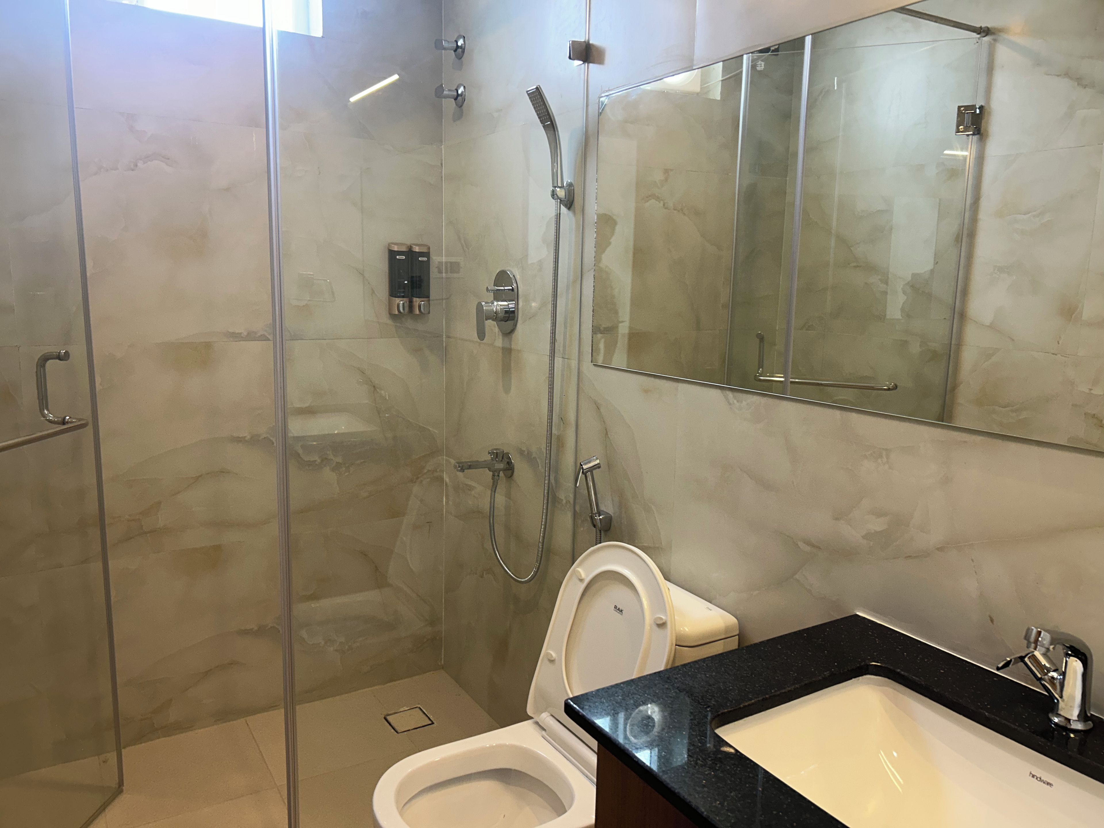 Ein modernes Badezimmer mit einer Duschkabine, einer Toilette und einem Waschbecken mit schwarzer Arbeitsplatte.