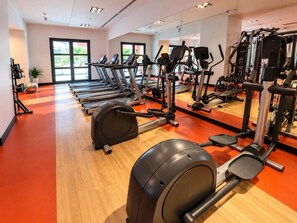 Une salle de sport équipée de tapis de course, de vélos elliptiques et d'appareils de musculation.