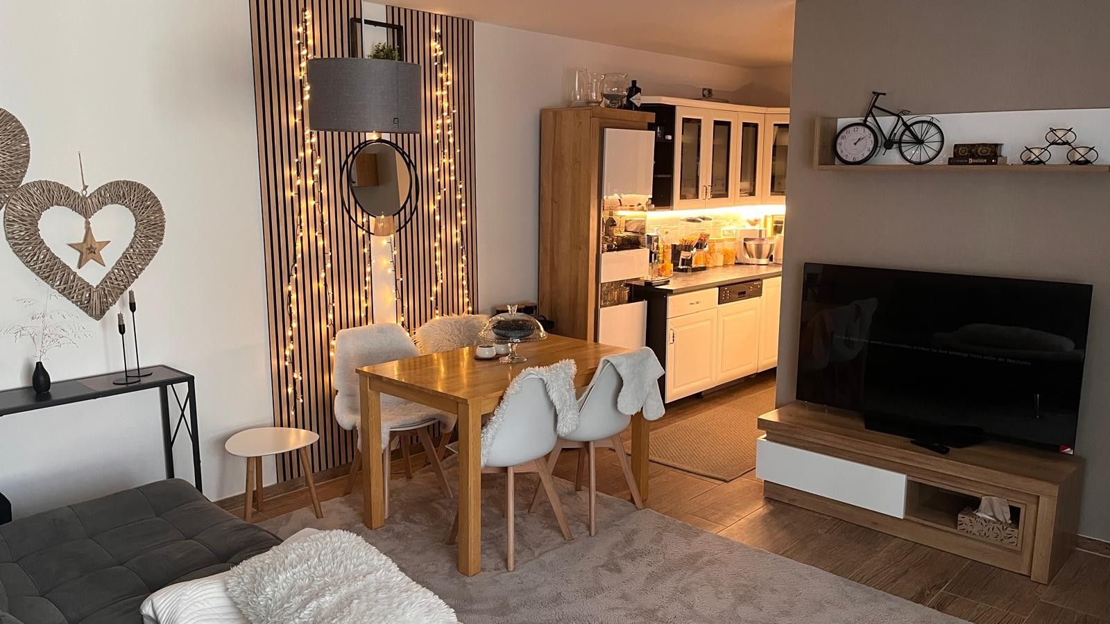 Una sala de estar moderna con comedor, cocina y televisor.