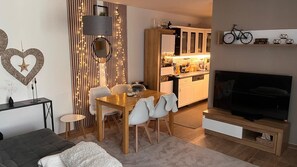 Una sala de estar moderna con comedor, cocina y televisor.