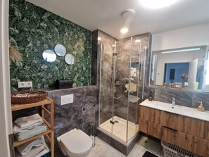 Een moderne badkamer met douchecabine, wastafelmeubel en toilet.