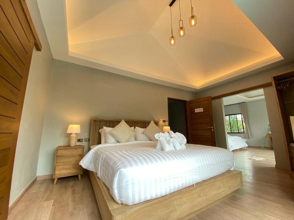 A bedroom with a large bed, wooden headboard, bedside tables, and a ceiling light fixture.