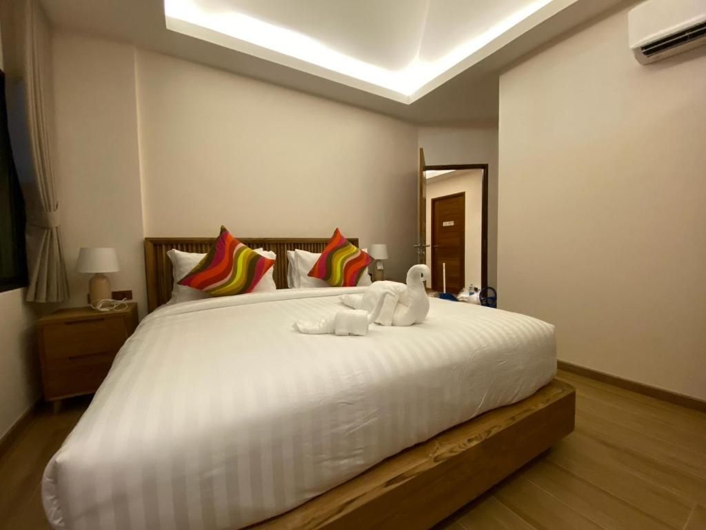 A hotel room with a large bed, a nightstand, a lamp, and a mirror.