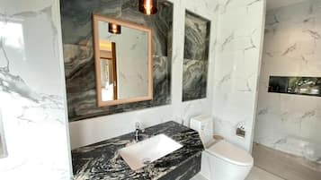 A bathroom with a marble sink, a toilet, and a mirror.