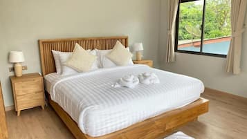 A bedroom with a wooden bed frame, white bedding, two bedside tables with lamps, and a window with a view of greenery.