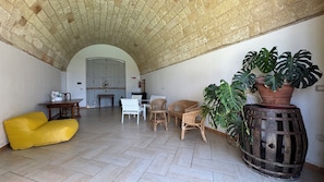 A spacious room with a high arched ceiling, a yellow bean bag, wicker furniture, and potted plants. - Luxury 5-bedroom country house with AC in charming Puglia inthe heart of Salento (Puglia)