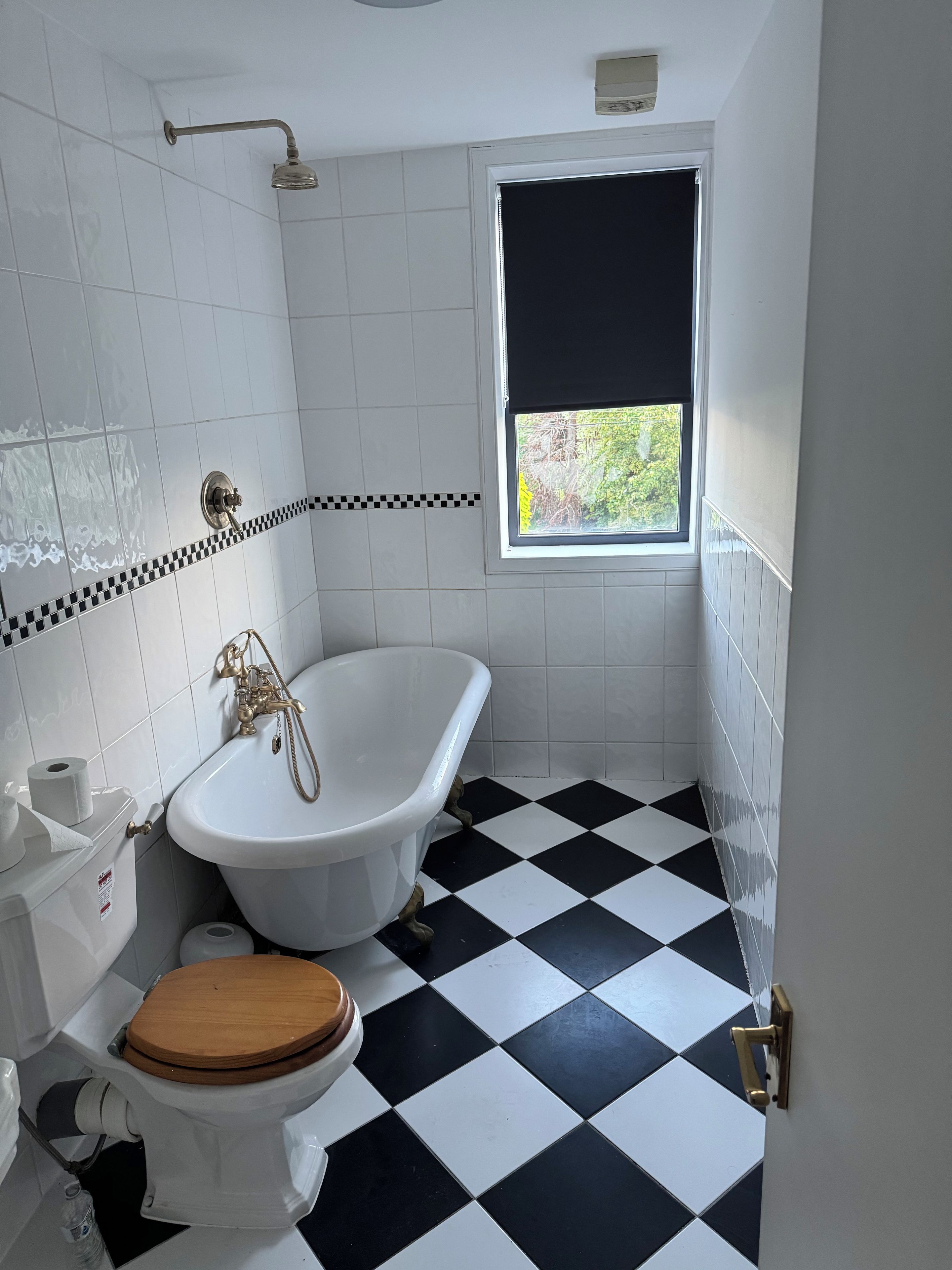 Une salle de bain avec une baignoire blanche, des toilettes et une fenêtre donnant sur un paysage verdoyant.