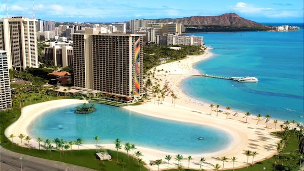 Un resort con acceso directo a la playa, una piscina grande y edificios altos al fondo.