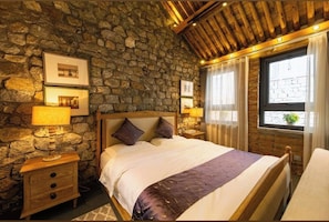 A bedroom with a stone wall, wooden headboard, bedside lamps, and a window with curtains. - Mutianyu Great Wall Castle Homestay (Huairou)