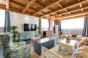A spacious living room with a high wooden ceiling, a television, and seating arrangements. - Mutianyu Great Wall Castle Homestay (Huairou)