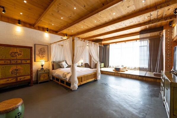 Una habitación con cama con dosel, techo de madera, pared de ladrillo y ventana con cortinas.
