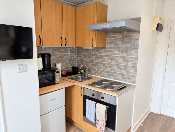 A compact kitchen with a microwave, stove, and oven.