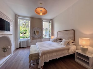 Une chambre à coucher avec un lit, une cheminée, une télévision et une vue sur la verdure.