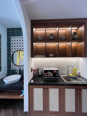 A modern kitchen with a built-in microwave, a sink, and a cabinet with decorative items. - Sujet Hotel Da Nang (Da Nang Municipality)